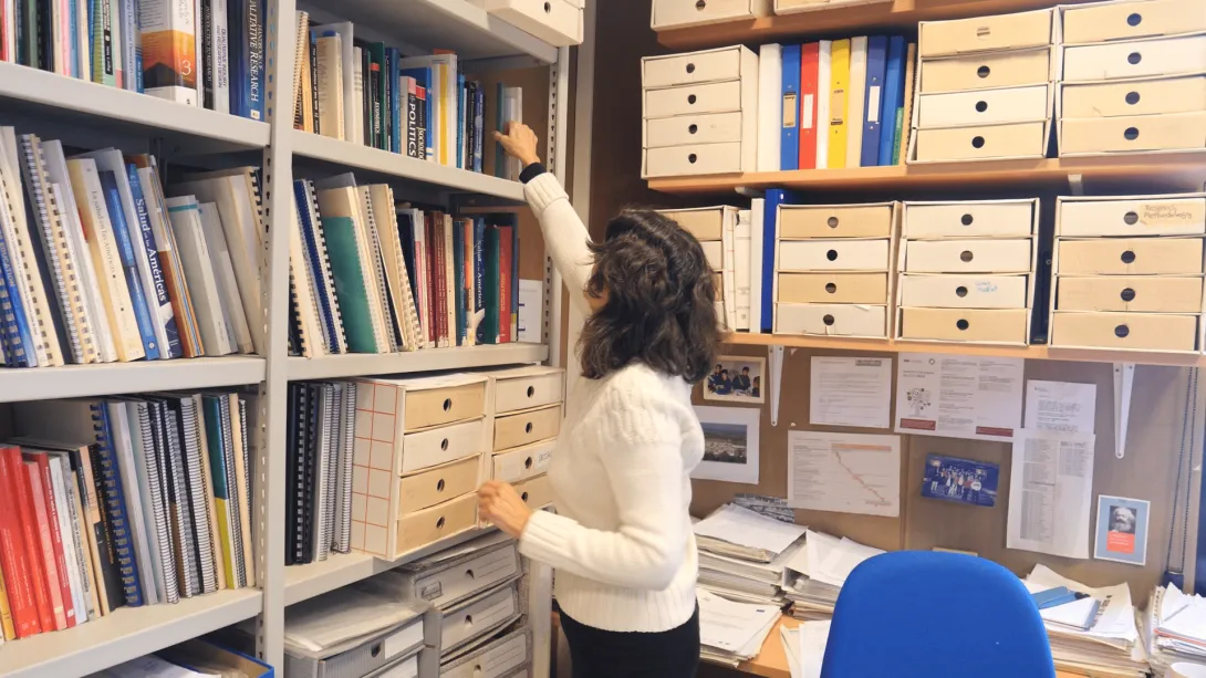 Professional de l'equip del SEPSS agafant un llibre de la prestatgeria